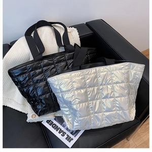 Detail of glossy black and silver quilted down tote bags on a leather sofa