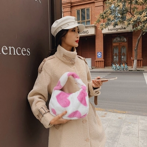 Sac sous le bras en peluche à motif vache rose et blanc, porté par un mannequin en ville