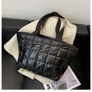 Macro detail of black quilted puffer tote bag fabric texture on modern leather sofa