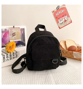 Detailaufnahme eines schwarzen Cord-Minirucksacks auf einem Schreibtisch mit Blumen
