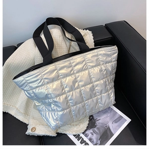 Detail of silver quilted tote bag with metallic finish on a white tweed jacket