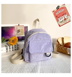 Detailansicht des lila Cord-Minirucksacks auf einem Schreibtisch mit Textur