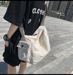 Macro detail of white canvas crossbody bag showing wide strap and front flap pocket