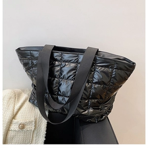 Detail view of high-gloss black quilted tote bag with diamond pattern and fabric strap