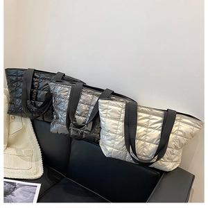 Quilted tote bags in black and champagne on a sofa, showing spacious design and glossy texture