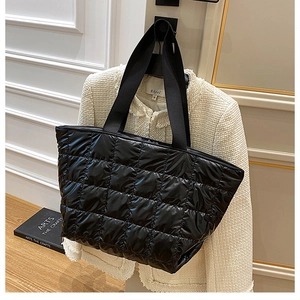 Detail of black quilted down tote bag with padded shoulder straps for daily commute
