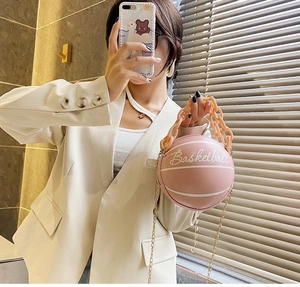 Pink basketball shaped crossbody bag with large plastic chain and metal strap detail