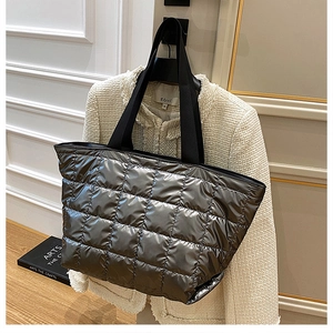 Detailed view of silver metallic quilted tote bag texture and wide black shoulder strap