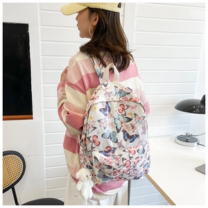 Detailed back view of white butterfly pattern backpack with cute white bear plush charm