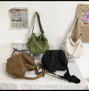 Detail view of canvas messenger bags in four colors with adjustable shoulder straps