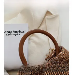 Close-up of brown resin handle and champagne gold rhinestones on a woven clutch bag