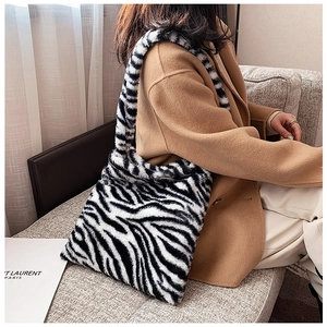 Detailed view of fluffy zebra print plush tote bag paired with a camel wool winter coat