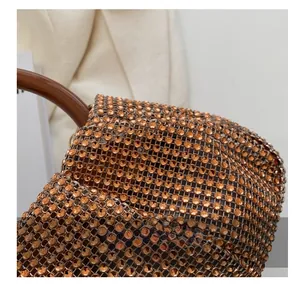 Macro shot of orange-gold rhinestones on a woven bag with a smooth brown handle