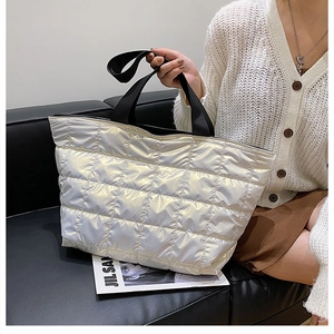 Macro detail of quilted puffer tote bag with metallic finish and black strap