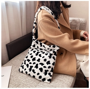 Detail of cow print plush tote bag with black and white faux fur and wide shoulder strap