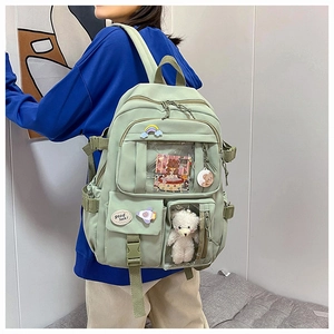 Detail view of light green nylon backpack with multi-pocket design and cute plush bear charm