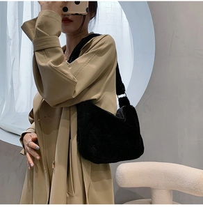 Chic black plush shoulder bag shown with a beige trench coat for winter style