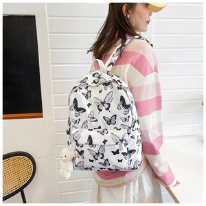 Detail of white butterfly print backpack with side pockets and cute plush bear charm