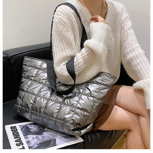Silver quilted metallic tote bag styled with wide black strap and white knit cardigan