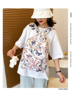 Detail of white butterfly print backpack with plush bear charm and stylish zippers