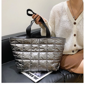 Silver quilted tote bag with black strap shown in a modern lifestyle setting