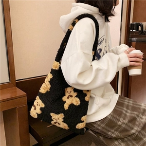 Detail of black fuzzy tote bag featuring brown teddy bear patterns and soft plush texture