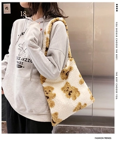 Detail view of cream plush tote bag with brown bear patterns and fleece shoulder strap