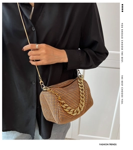 Close-up of golden rhinestone cylinder evening bag with chunky metal chain handle