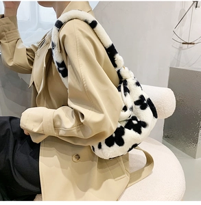 Detail of soft plush cow print shoulder bag with fluffy wide strap on beige trench coat