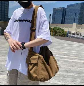 Brown canvas messenger bag side view showing utility snap pocket and adjustable strap