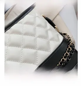 Detailed close-up of monochrome quilted leather texture and gold-silver chain strap