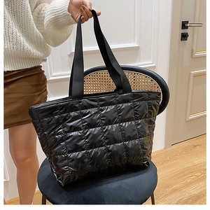 Detail of a large black quilted tote bag showing padded fabric and sturdy straps