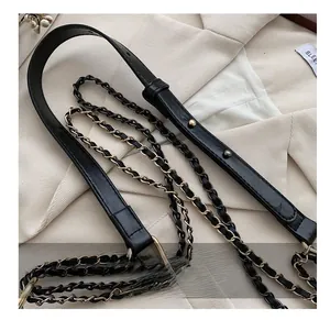 Detailed macro view of adjustable black leather shoulder strap and woven decorative chains