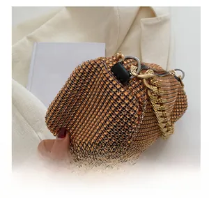 Detail of a mini bucket bag with orange rhinestones and a chunky gold chain strap