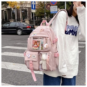 Outdoor shot of a pink Japanese style backpack featuring a bear pendant and clear pocket
