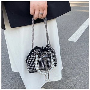 Detail of a black bucket bag with silver rhinestones, pearl handle, and metal chain