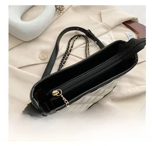 Detail view of the smooth black zipper and white quilted texture of the shoulder bag