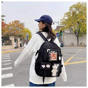 Detail of black multi-pocket student backpack with clear PVC pocket and cute bear charm