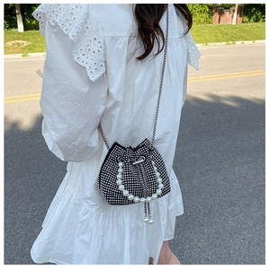 Detailed macro of a black velvet bucket bag with sparkling rhinestones and pearl handle