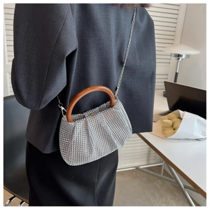 Detail of silver rhinestone woven bag with wooden handle and metallic chain strap for women