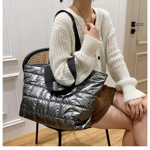 Detail of silver metallic quilted puffer tote bag with wide black shoulder straps on model