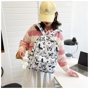 Detailed shot of white butterfly print student backpack with a small plush bear keychain