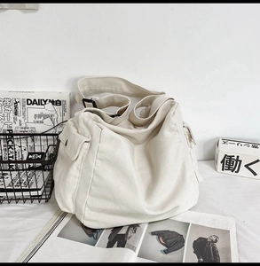Detail of a cream canvas messenger bag with adjustable strap and side pocket design