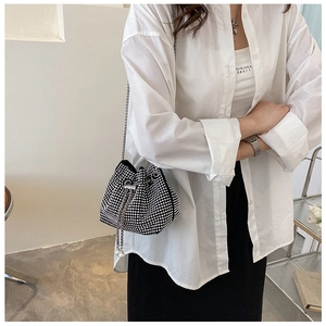 Detail of black rhinestone bucket bag featuring chain strap and pearl drawstring tassels