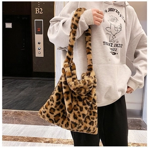 Close-up of leopard print plush tote bag showing soft faux fur texture and wide shoulder strap