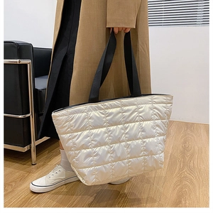 Close-up of white quilted puffer tote bag with black strap handles in home setting