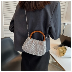 Detail view of silver rhinestone woven bag with round handle and metal chain on a model
