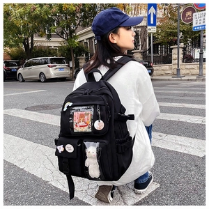 Close-up of black campus backpack with cute plush charm and decorative luck badges