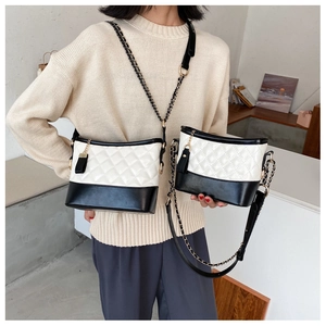 Detail of quilted leather hobo bag with monochrome design and chain strap with tassel