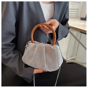 Detail of silver rhinestone evening bag featuring a brown round handle and chain strap